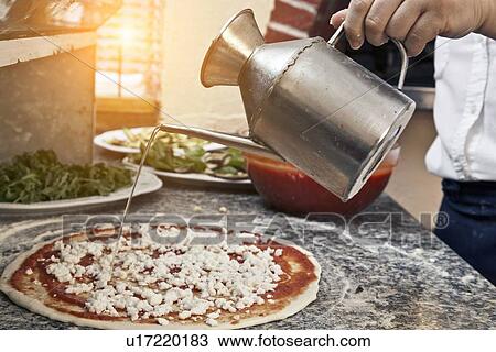 Chef pouring oil on uncooked pizza View Large Photo Image Stock Image - Chef pouring oil on uncooked pizza. Fotosearch
