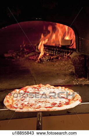 Stock Image - Chef pulling pizza from oven. Fotosearch