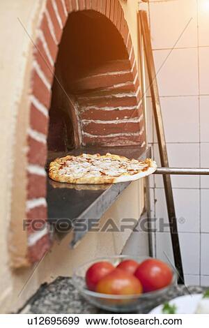 Stock Photo - Chef pulling pizza from oven. Fotosearch