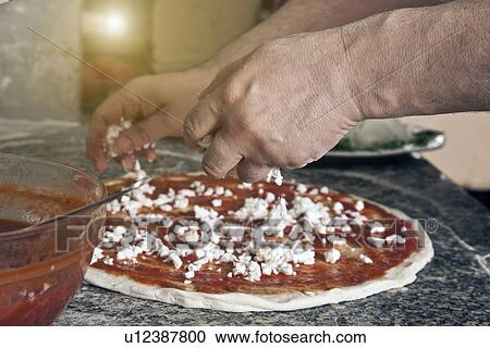 Chef sprinkling cheese on uncooked pizza View Large Photo Image Stock Image - Chef sprinkling cheese on uncooked pizza. Fotosearch