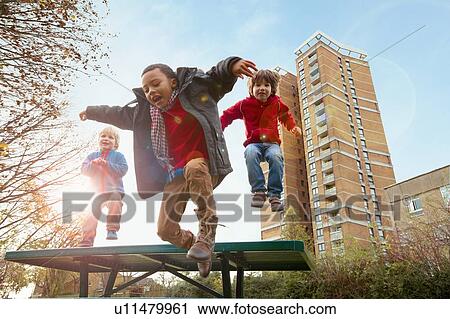 Stock Image - Children jumping for joy in park. Fotosearch