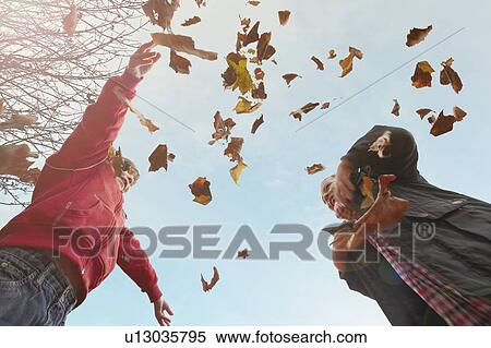 Stock Photography - Children playing with autumn leaves. Fotosearch