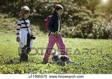 Stock Image - Children walking dog in field. Fotosearch