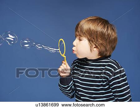 Stock Photo - Close up of boy blowing bubbles. Fotosearch