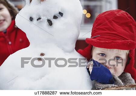 Stock Photo - Close up of boy hugging snowman. Fotosearch