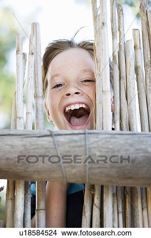 Close up of boy smiling behind fence View Large Photo Image Picture - Close up of boy smiling behind fence. Fotosearch