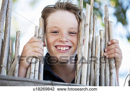 Close up of boy smiling behind fence View Large Photo Image Stock Image - Close up of boy smiling behind fence. Fotosearch