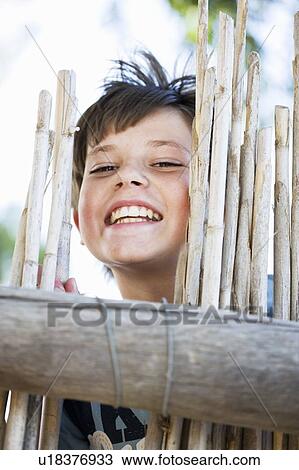 Close up of boy smiling behind fence View Large Photo Image Stock Image - Close up of boy smiling behind fence. Fotosearch