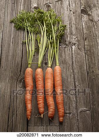 Stock Image - Close up of carrots on wooden table. Fotosearch