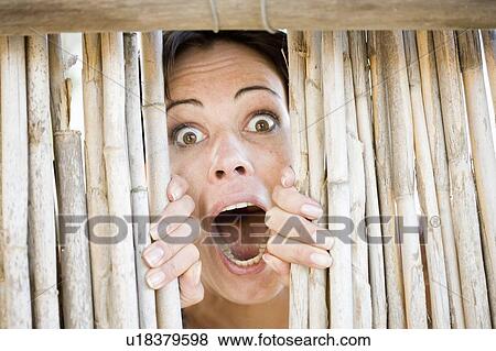 Stock Photo - Close up of woman gasping behind fence. Fotosearch