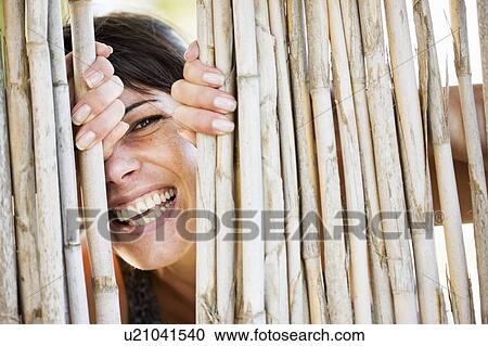 Close up of woman smiling behind fence View Large Photo Image Stock Image - Close up of woman smiling behind fence. Fotosearch