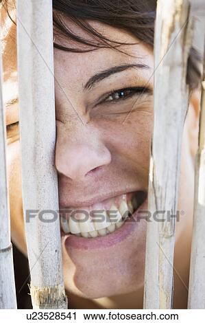 Close up of woman smiling behind fence View Large Photo Image Stock Image - Close up of woman smiling behind fence. Fotosearch
