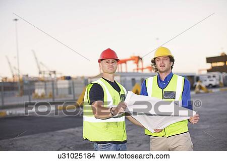 Picture - Construction workers reading blueprint. Fotosearch
