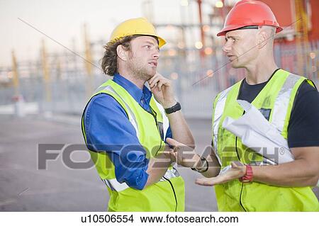 Picture - Construction workers talking on site. Fotosearch