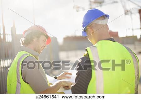 Stock Image - Construction workers talking on site. Fotosearch