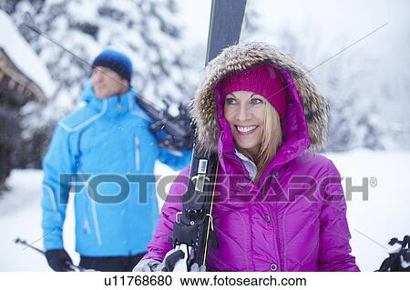 Couple carrying skis and poles in snow View Large Photo Image Stock Image - Couple carrying skis and poles in snow. Fotosearch
