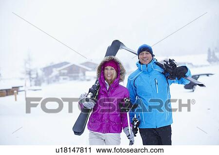 Couple carrying skis and poles in snow View Large Photo Image Stock Image - Couple carrying skis and poles in snow. Fotosearch