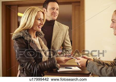 Stock Image - Couple checking in to hotel. Fotosearch