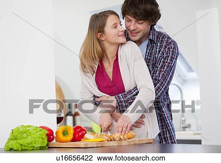 Stock Image - Couple cooking together in kitchen. Fotosearch