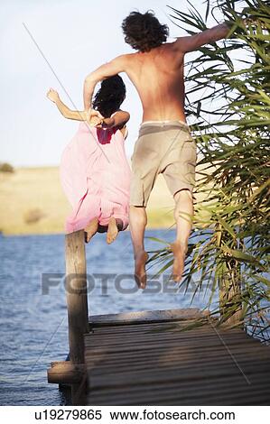 Couple jumping off dock into lake View Large Photo Image Stock Photography - Couple jumping off dock into lake. Fotosearch