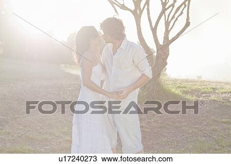 Couple kissing in field View Large Photo Image Stock Image - Couple kissing in field. Fotosearch