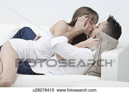 Stock Image - Couple kissing on couch. Fotosearch