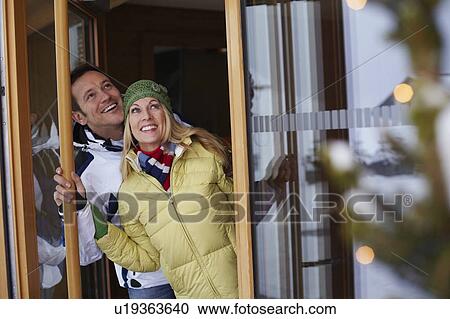 Stock Image - Couple looking out glass door. Fotosearch