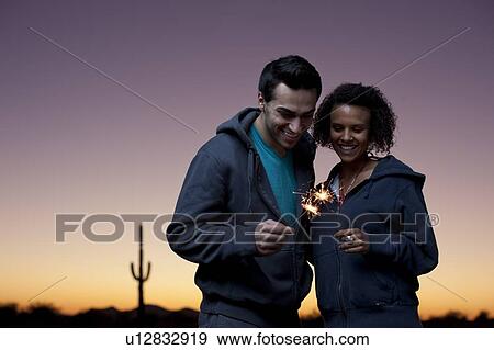 Stock Photo - Couple playing with sparklers in desert. Fotosearch