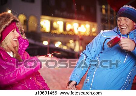 Stock Photography - Couple pulling Christmas cracker in snow. Fotosearch