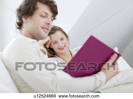 Couple reading together on sofa View Large Photo Image Stock Photo - Couple reading together on sofa. Fotosearch