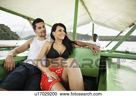Stock Image - Couple relaxing on boat in river. Fotosearch