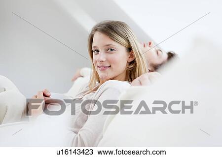 Stock Image - Couple relaxing together on sofa. Fotosearch