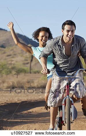 Stock Photo - Couple riding bicycle on dirt road. Fotosearch