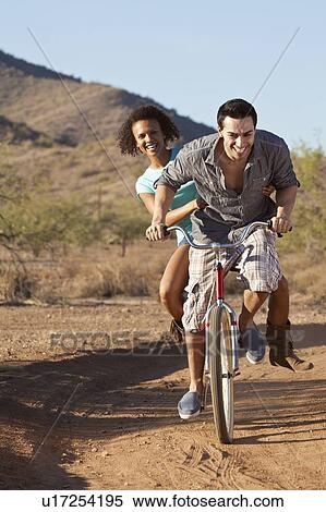 Stock Photography - Couple riding bicycle on dirt road. Fotosearch