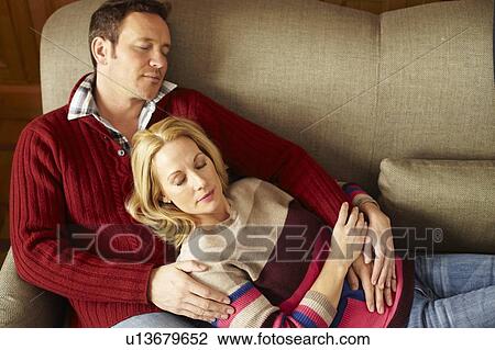 Stock Image - Couple sleeping on sofa together. Fotosearch