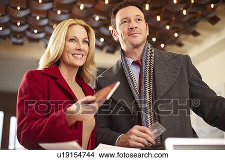Picture - Couple standing at hotel front desk. Fotosearch