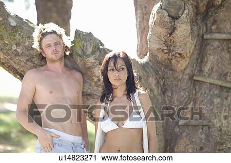 Stock Image - Couple standing by tree outdoors. Fotosearch