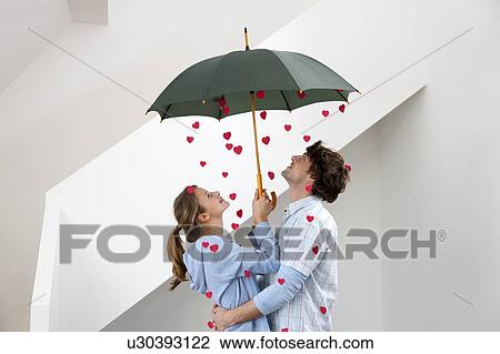 Couple standing under shower of hearts View Large Photo Image Stock Image - Couple standing under shower of hearts. Fotosearch
