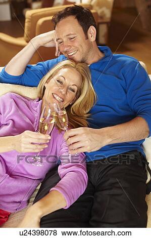 Couple toasting each other on sofa View Large Photo Image Stock Photo - Couple toasting each other on sofa. Fotosearch