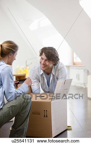 Stock Image - Couple unpacking cardboard box. Fotosearch