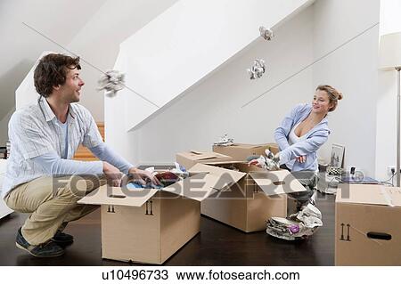 Stock Image - Couple unpacking cardboard boxes. Fotosearch