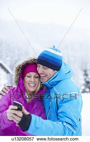 Couple using cell phone together in snow View Large Photo Image Stock Photo - Couple using cell phone together in snow. Fotosearch
