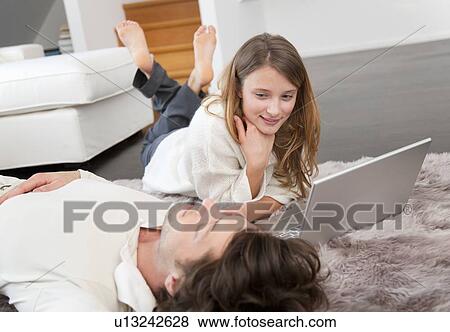 Couple using laptop together on rug View Large Photo Image Stock Photo - Couple using laptop together on rug. Fotosearch