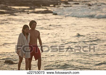 Stock Image - Couple walking together on beach. Fotosearch