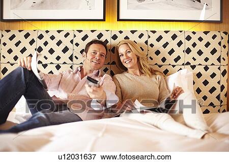 Couple watching television on bed View Large Photo Image Stock Photo - Couple watching television on bed. Fotosearch