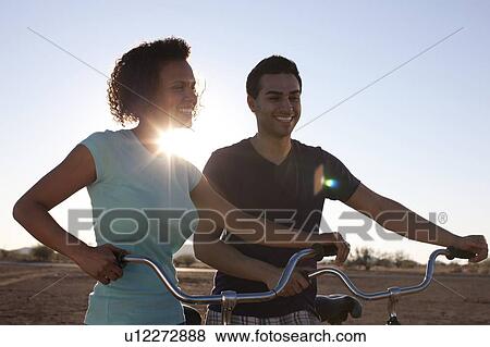 Stock Photo - Couple with bicycles in desert landscape. Fotosearch