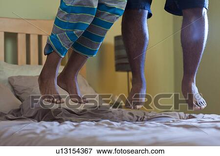 Stock Photo - Couples feet jumping on bed. Fotosearch