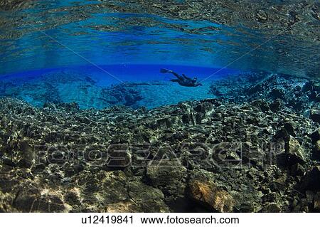 Diver swimming by rock formations View Large Photo Image Stock Image - Diver swimming by rock formations. Fotosearch
