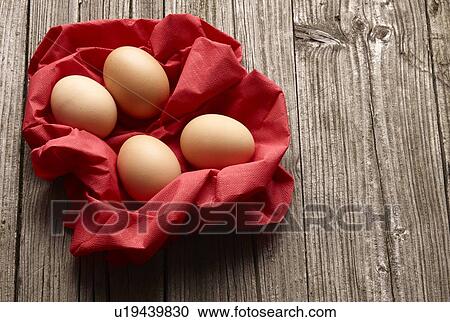 Stock Image - Eggs in paper basket on wooden table. Fotosearch