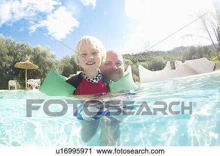 Stock Image - Father and son playing in pool. Fotosearch